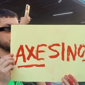HOMBRE SOSTIENE CARTEL QUE DICE AXESINOS