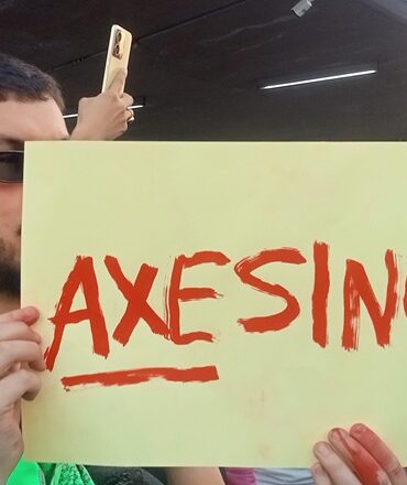 HOMBRE SOSTIENE CARTEL QUE DICE AXESINOS