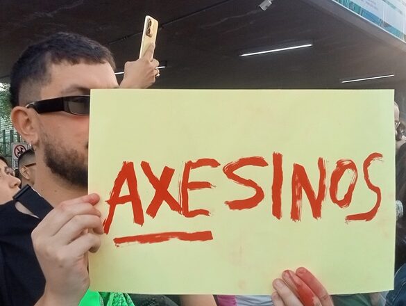 HOMBRE SOSTIENE CARTEL QUE DICE AXESINOS
