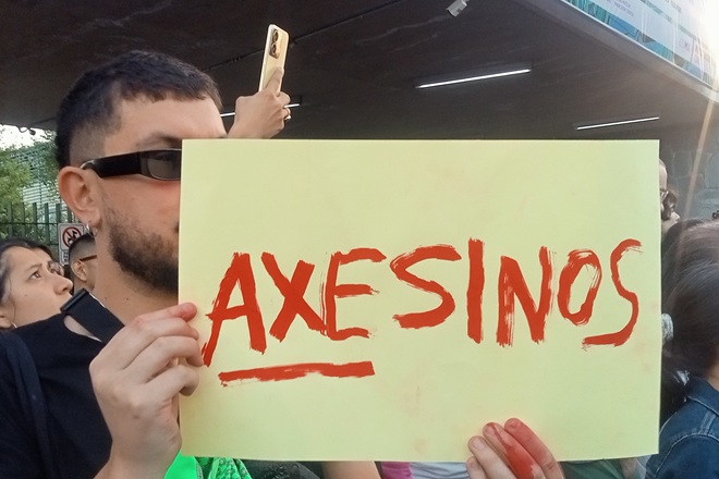 HOMBRE SOSTIENE CARTEL QUE DICE AXESINOS