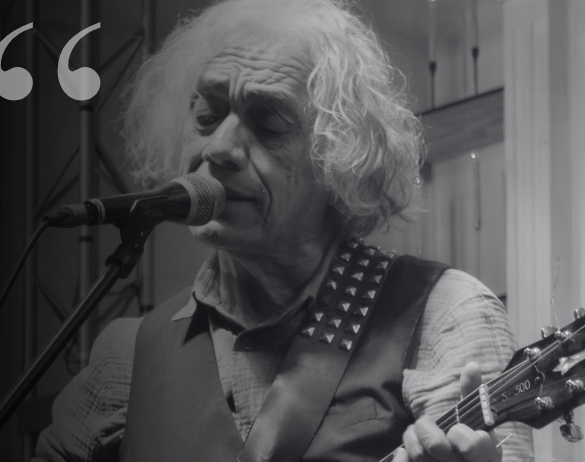 Arturo Meza canta frente a un micrófono y toca una guitarra